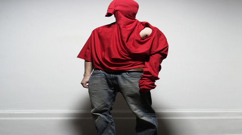 A model wears a highly irregular shirt with a sleeve for a neck hole