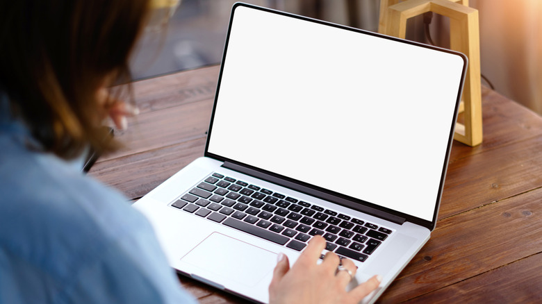 A person looking at a laptop with a white screen