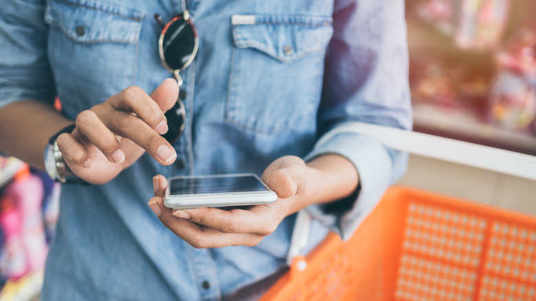 A person compares prices on their phone while shopping