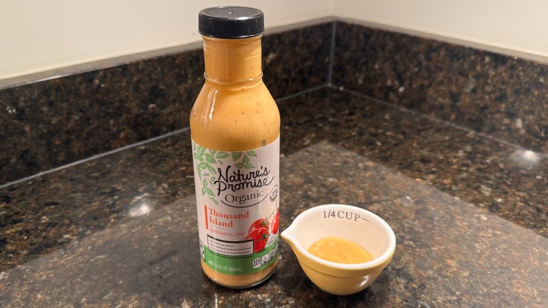 Bottle and small bowl of Nature's Promise Thousand Island Dressing on black countertop
