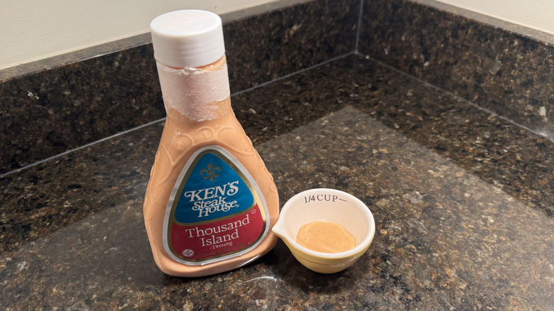 Bottle and small bowl of Ken's Steak House Thousand Island Dressing on black countertop