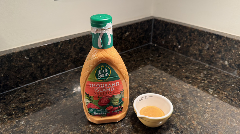 Bottle and small bowl of Wish-Bone Thousand Island Dressing on black countertop