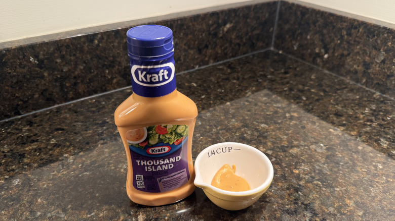 Bottle and small bowl of Kraft Thousand Island Dressing on black countertop