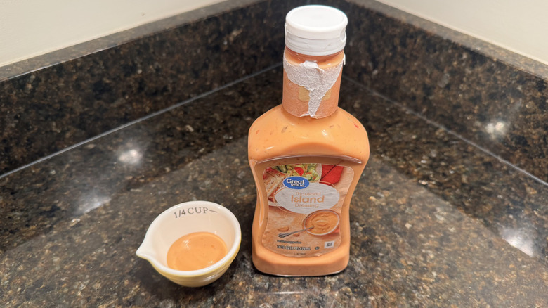 Bottle and small bowl of Great Value Thousand Island Dressing on black countertop