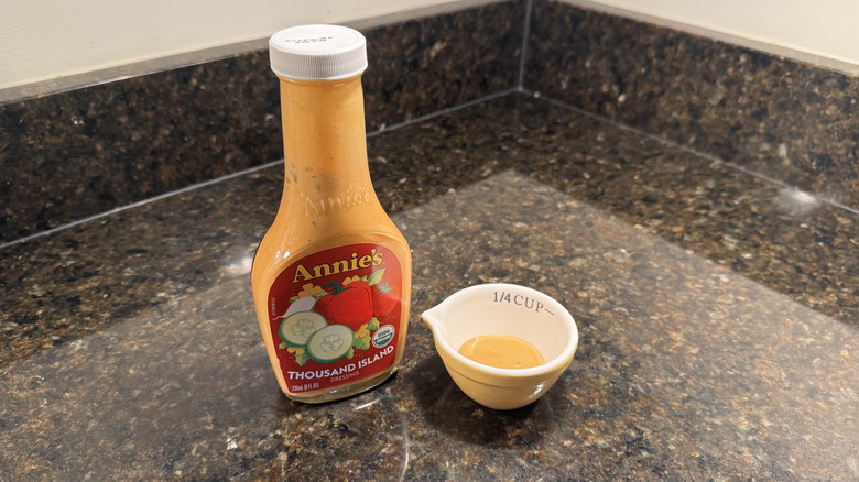 Bottle and small bowl of Annie's Organic Thousand Island Dressing on black countertop