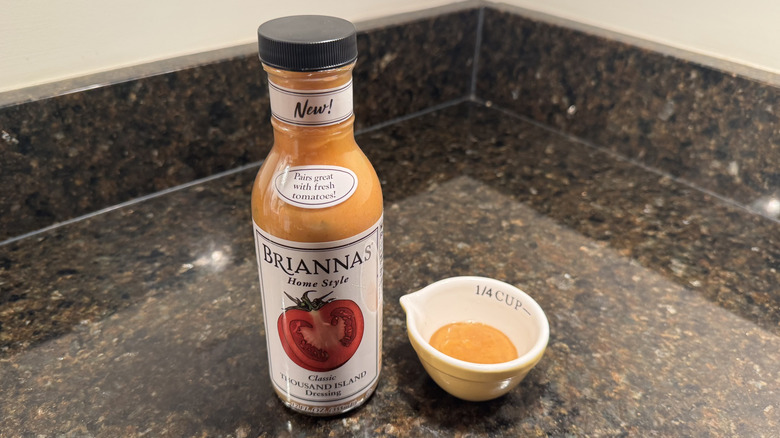 Bottle and small bowl of Briannas Thousand Island Dressing on black countertop