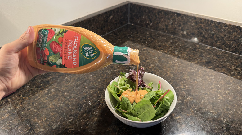 Pouring Wish-Bone Thousand Island Dressing on bowl of lettuce
