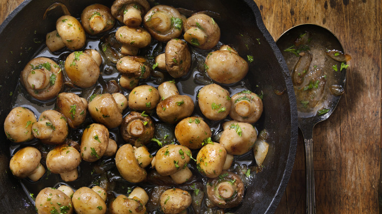 Cooked mushrooms with herbs in a cast iron pan