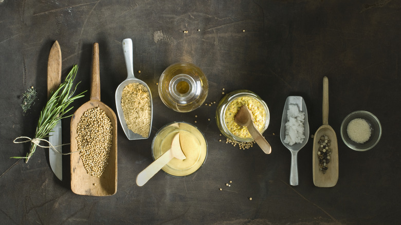 A selection of spices, mustard seeds, and oils in small containers photographed from above