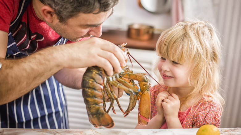 Child looking at person holding lobster
