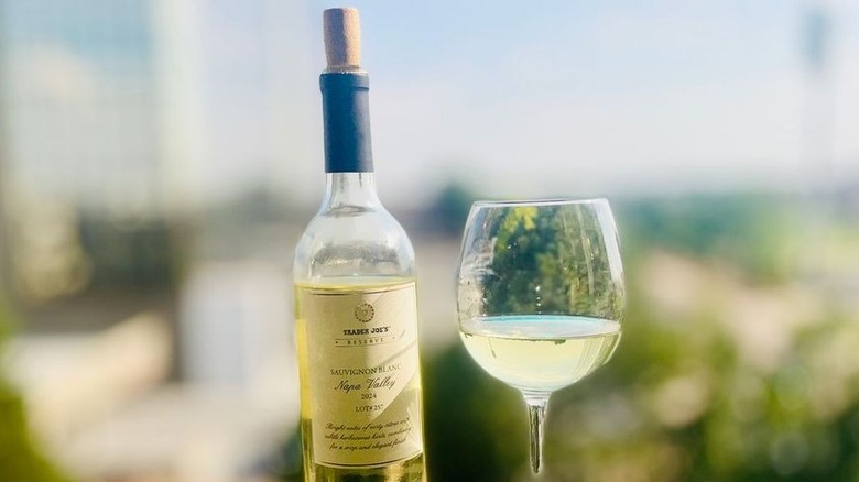A bottle and a glass of Trader Joe's Reserve Sauvignon Blanc Lot #257 sitting on an outdoor ledge