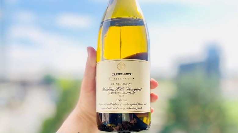 A bottle and a glass of Trader Joe's Reserve Chardonnay sitting on outdoor ledge in sunlight