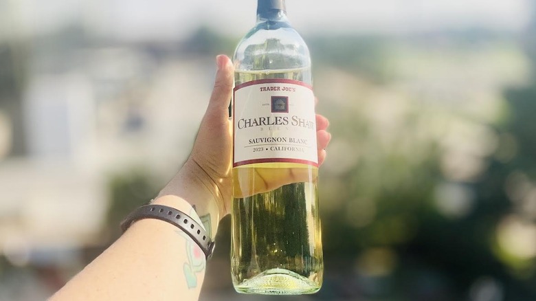 A person holding a bottle of Charles Shaw Sauvignon Blanc