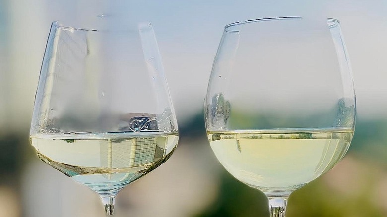 Two glasses of white wine sitting on an outdoor ledge
