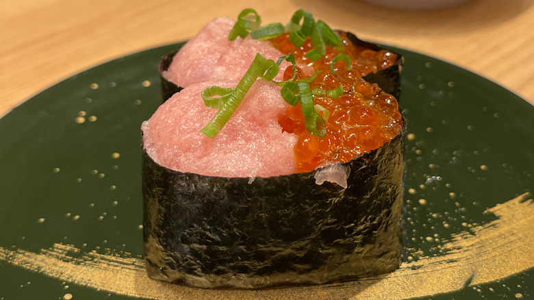 two tuna and salmon roe gunkan rolls on a green plate