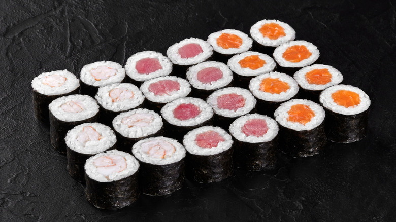 a variety of hosomaki on a black background