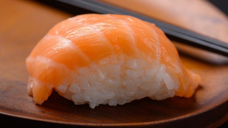 close-up shot of a salmon nigiri with chopsticks