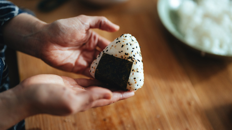 an angle view of a man holding an onigiri