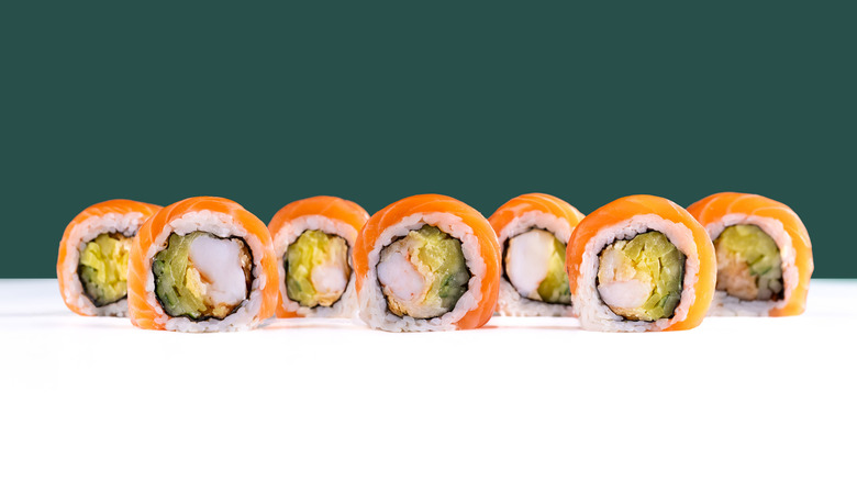 salmon and shrimp uramaki on white and turquoise background