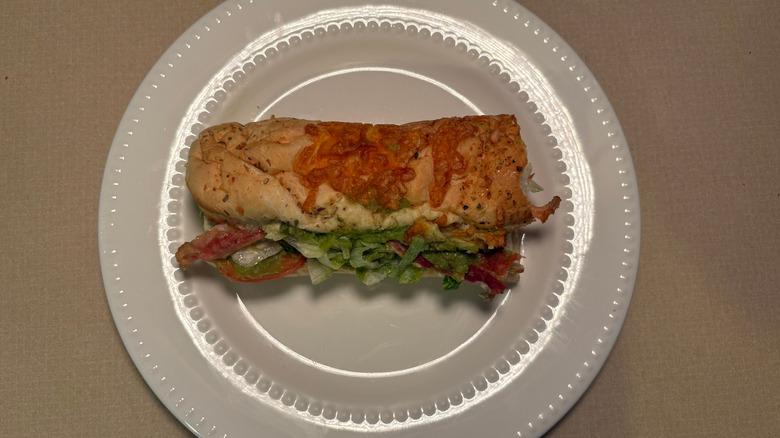 A BLT with avocado on italian herbs and cheese