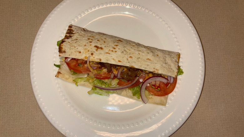 A flatbread with steak, chipotle sauce, and veggies on a plate.