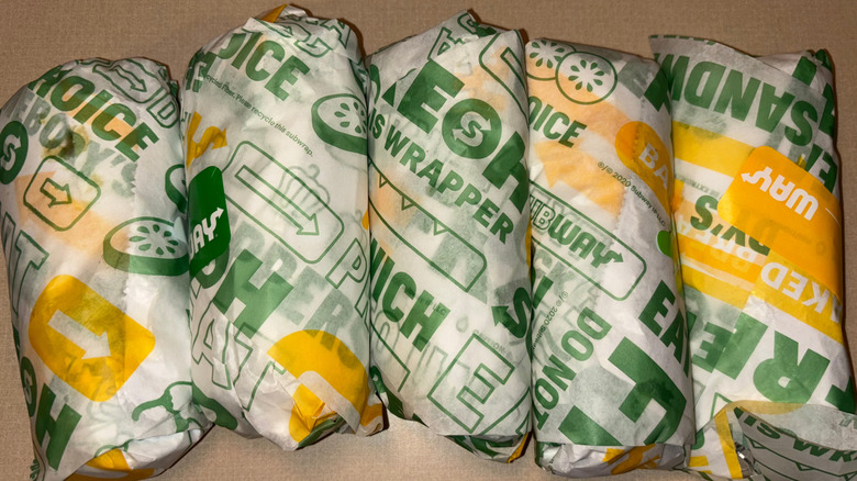 Five wrapped Subway six-inch subs on a counter