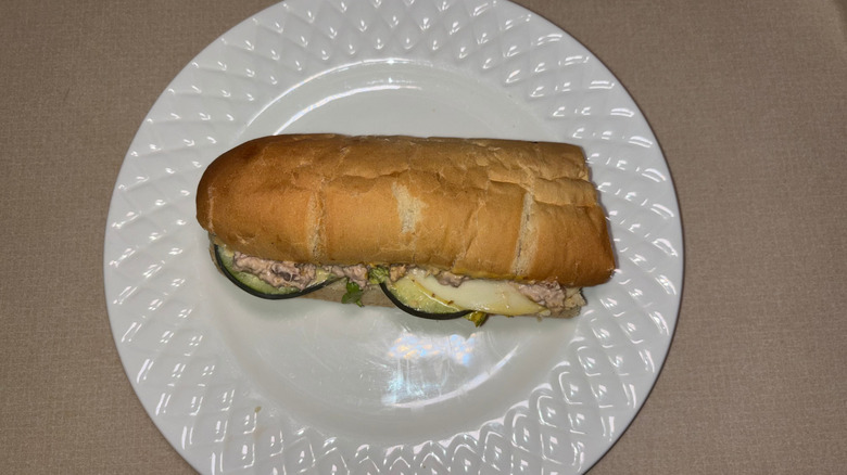 A tuna sub on white bread with cucumber and provolone