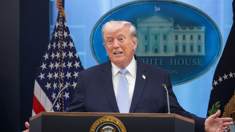 President Donald Trump at a podium with two flags on either side