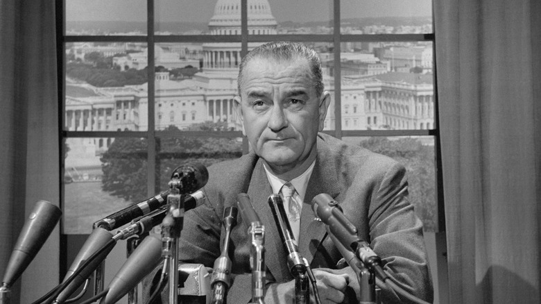 President Lyndon B. Johnson in front of a window with a view of the U.S. Capitol Building