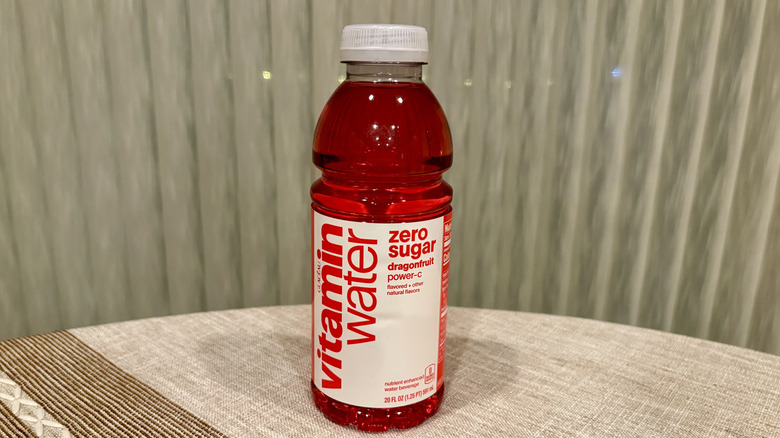A Power-C Zero Sugar Dragonfruit Vitaminwater sitting on a table in front of a white curtain