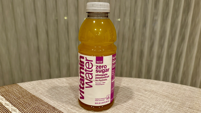 A Re-Hydrate Zero Sugar Pineapple Passionfruit Vitaminwater sitting on a table in front of a white curtain