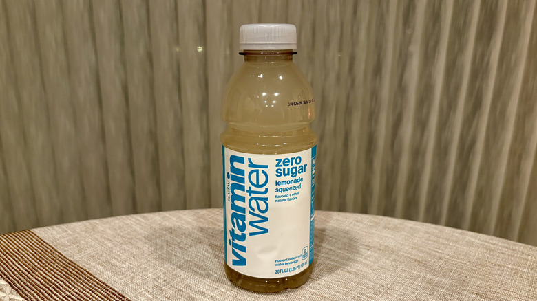 A Zero Sugar Squeezed Lemonade Vitaminwater sitting on a table in front of a white curtain