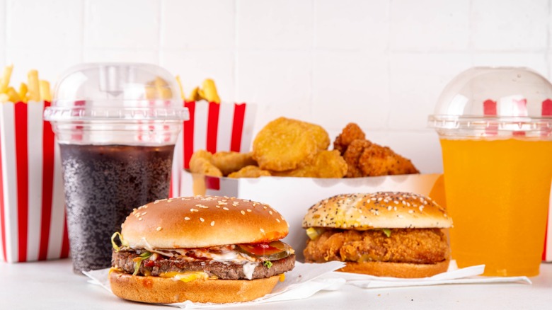 A fast food burger, chicken sandwich, drinks, and fried foods with a white background