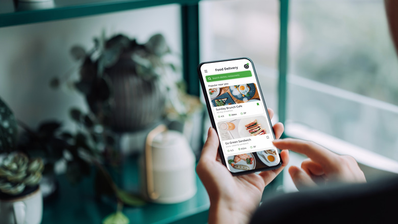 A person holds their phone depicting a food delivery app