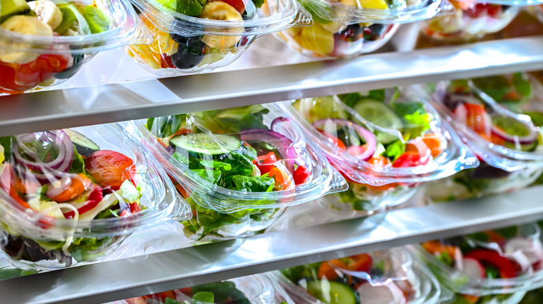 A glass case filled with packaged salads and fruit
