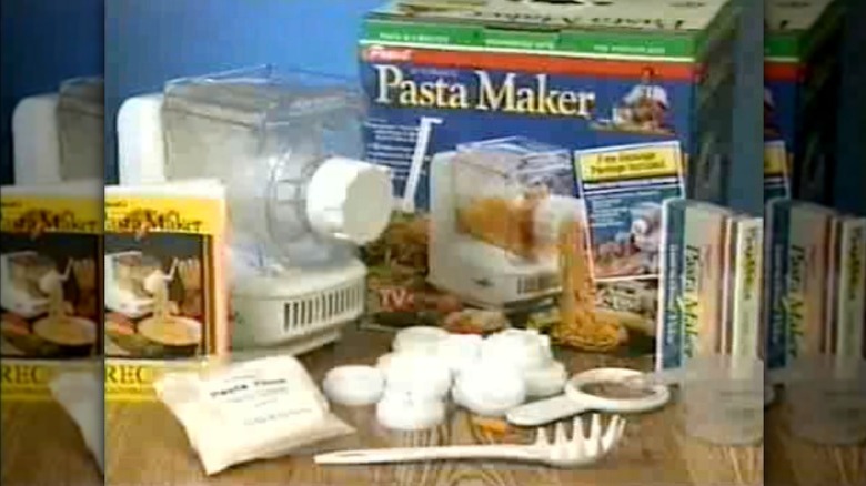 1990s Ronco pasta maker and assorted accessories laid out on a table during the infomercial