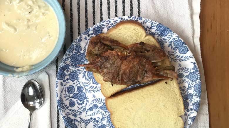 fried soft-shell crab sitting on white bread with sauce