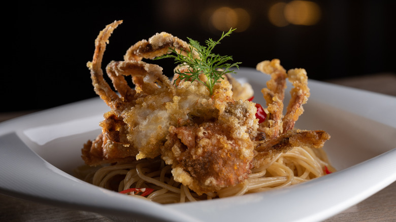 fried soft-shell crab on plate of pasta