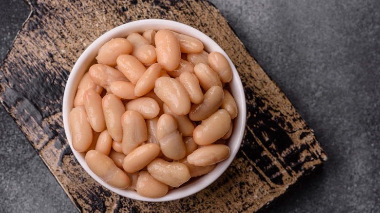An bowl of canned white beans on a wooden board