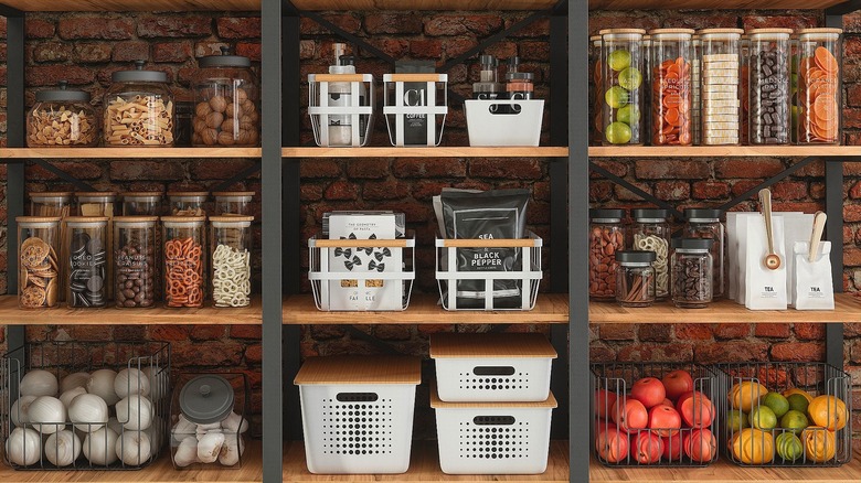 Organized pantry wall with glass containers and white baskets with wooden lids