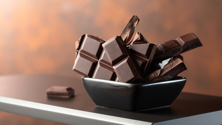 Broken pieces of a dark chocolate bar in a bowl.