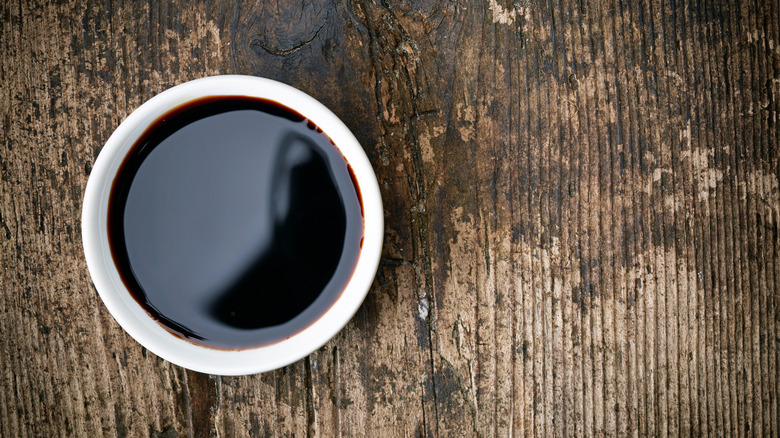 Bowl of balsamic vinegar on a wooden table.