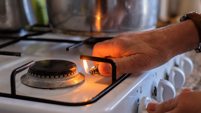 person lighting gas stovetop with lighter due to failed igniter