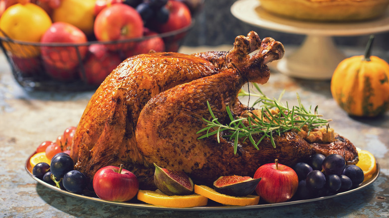 Roasted Thanksgiving turkey on a plate with fruit and herbs