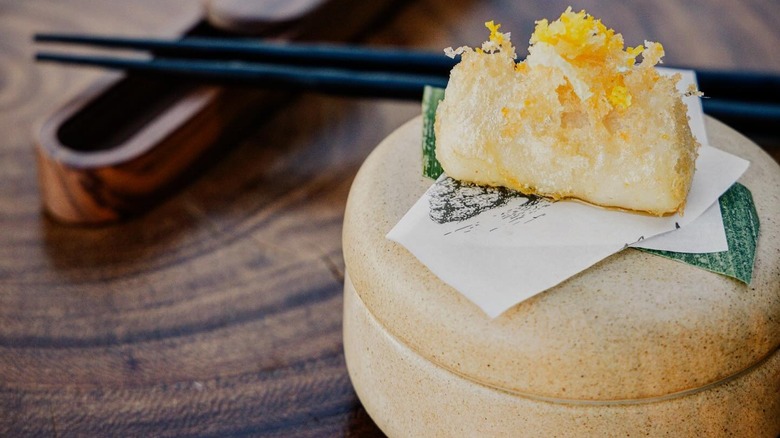A black cod amuse bouche on a stone plate at Animalón in Valle de Guadalupe