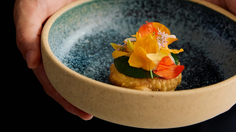 A person holding a fine dining dish at Quintonil in Mexico City