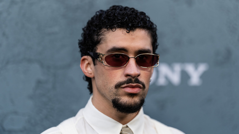 Bad Bunny posing for the camera, wearing red-tinted shades