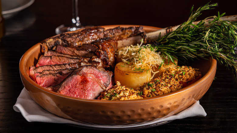 Bowl of sliced steak, potatoes, and rosemary