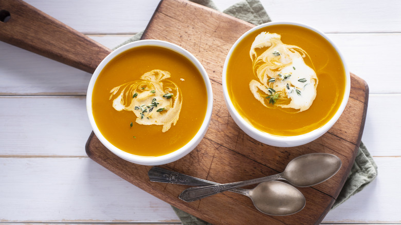 butternut squash soup in two bowls with herbs