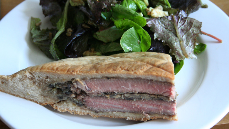 A shooter's sandwich on a plate with salad.